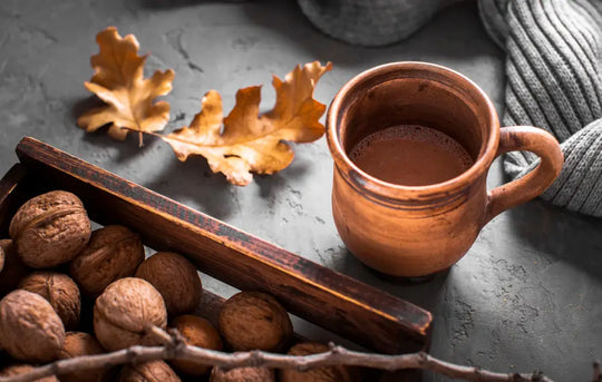 A warm cacao drink surrounded by natural ingredients like cacao beans, cinnamon, and lavender on a rustic table